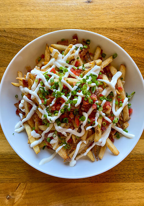 Fully loaded fries with sour cream, green onions, bacon, and tomatoes