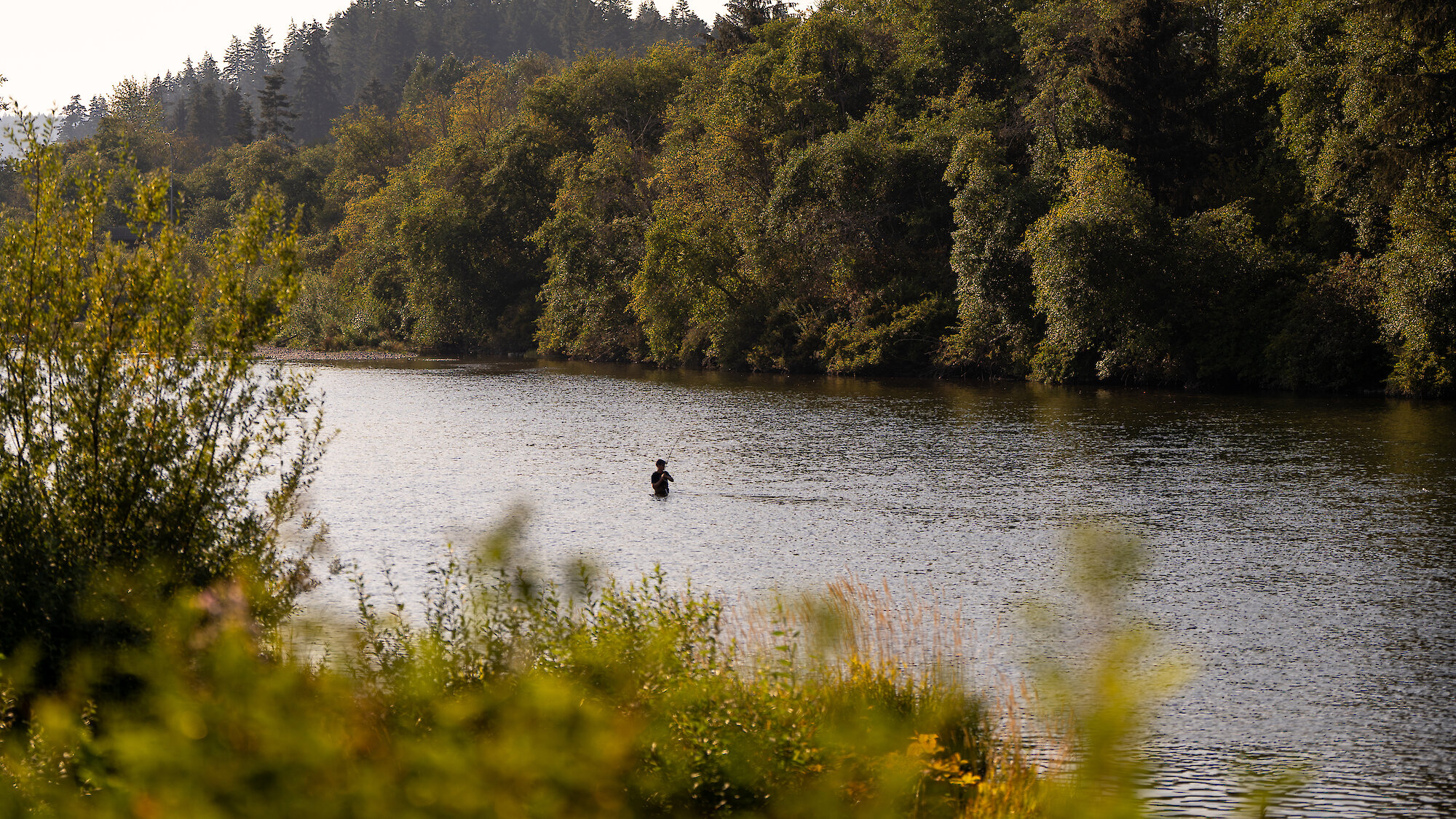 A snowboarder heads down Mount Washington on a blue and cloudy sky, with a clear view of the Comox Valley below.