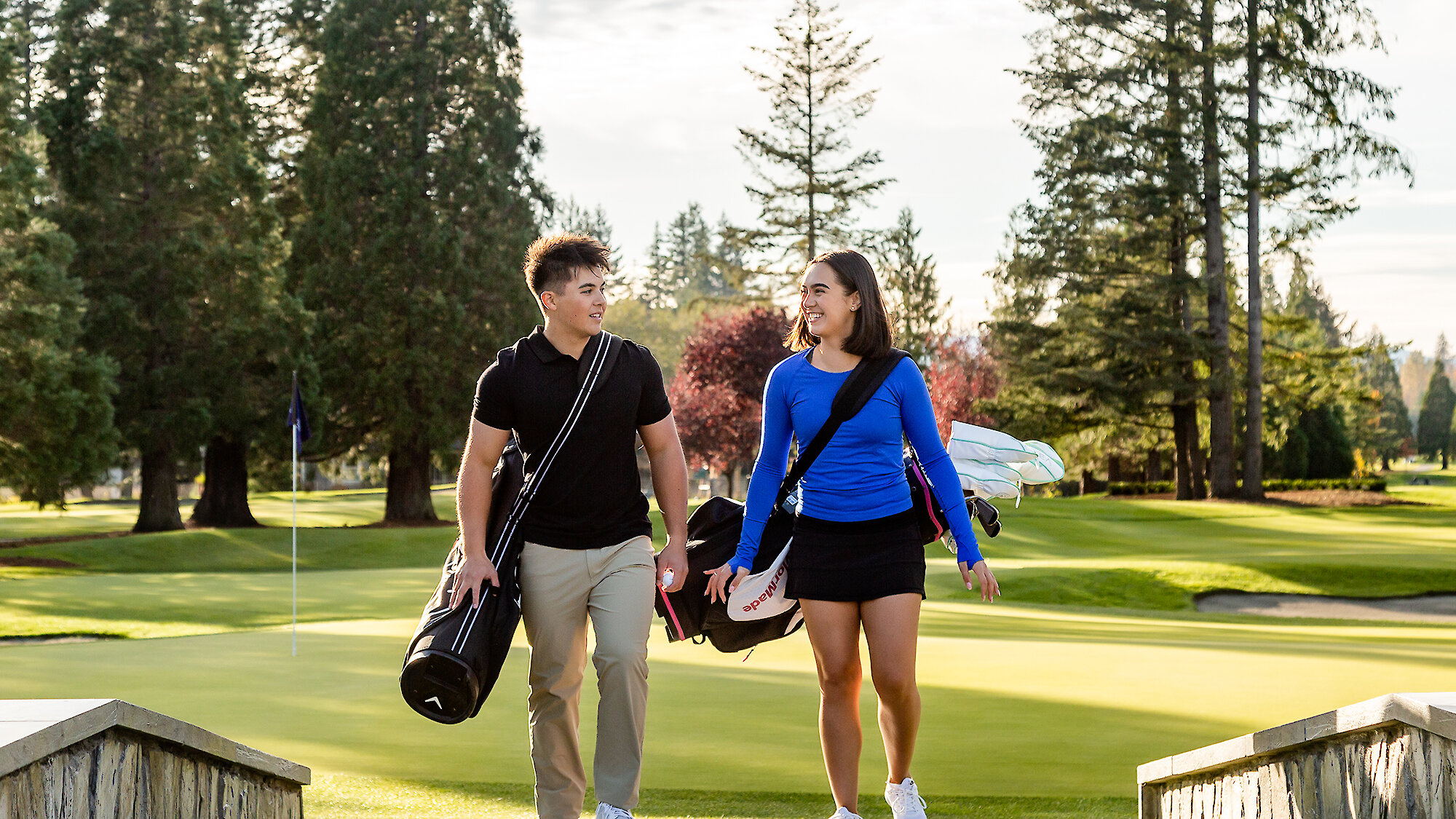 A male and female golfer cross a bridge at the Campbell River Golf Clubs hole 18.