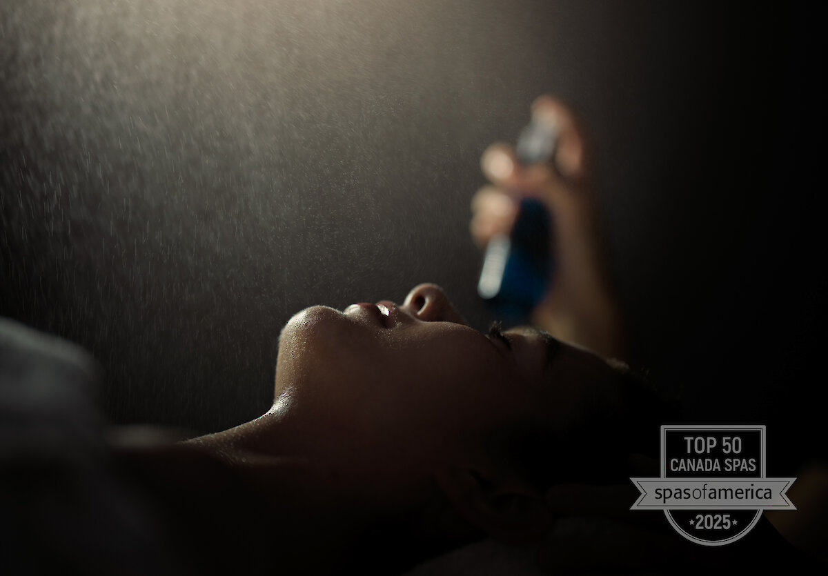 guest on massage table with practitioner spraying a soothing mist