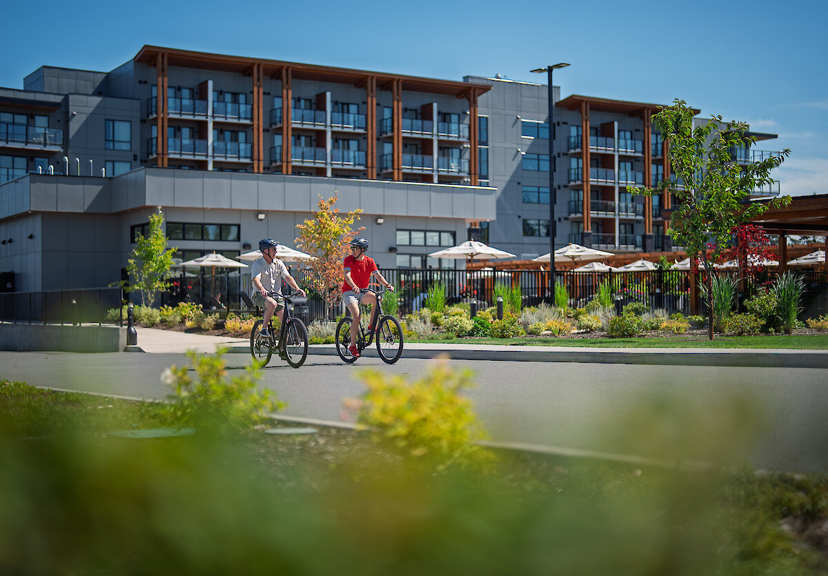 Two men biking along the road with Naturally Pacific Resort in the background